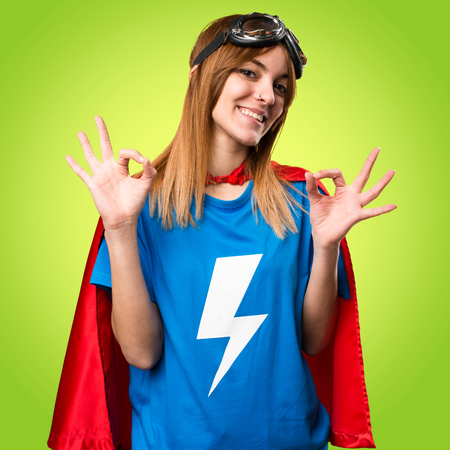 Pretty superhero girl making OK sign on colorful backgroundの写真素材