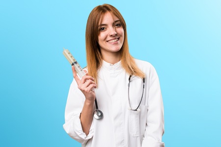 Young doctor woman holding a syringe on colorful backgroundの写真素材