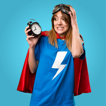 Pretty superhero girl holding vintage clock on colorful backgroundの写真素材
