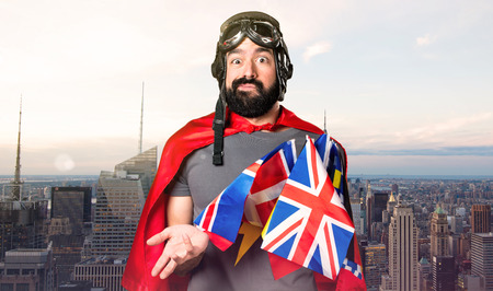 Superhero with a lot of flags making surprise gesture on unfocused city backgroundの写真素材