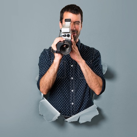 Brunette man filming through a paper hole