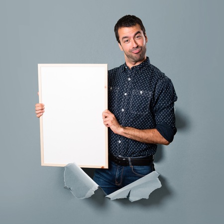 Happy Brunette man holding an empty placard through a paper holeの写真素材