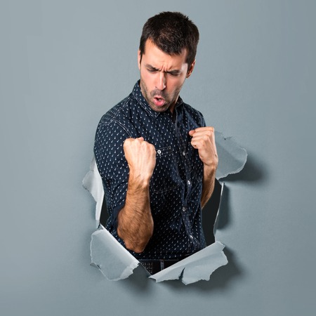 Lucky brunette man through a paper holeの写真素材