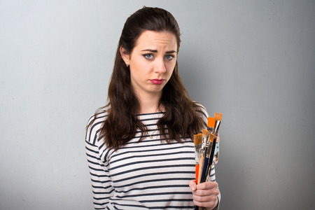 Sad young artist woman on grey backgroundの写真素材