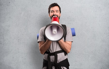 Handsome backpacker holding a megaphone on textured backgroundの写真素材