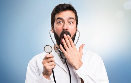 Young doctor with stethoscope on blue backgroundの写真素材