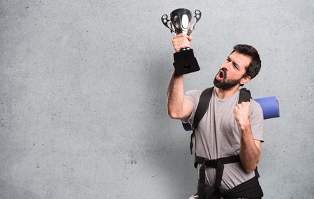 Happy Handsome backpacker holding a trophy on textured backgroundの写真素材