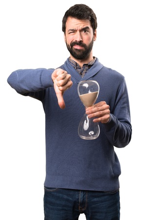 Sad Handsome brunette man with beard holding a sand clock on white background