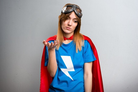 Tired pretty superhero girl on a gray textured backgroundの写真素材