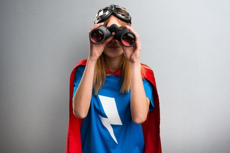 Pretty superhero girl with binoculars on a gray textured backgroundの写真素材