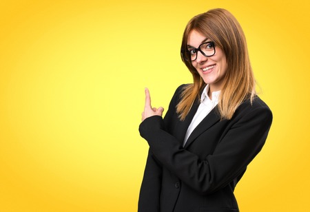 Young business woman pointing back on colorful backgroundの写真素材