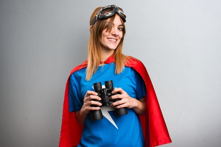 Pretty superhero girl with binoculars on a gray textured backgroundの写真素材