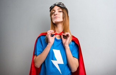 Pretty superhero girl proud of herself on a gray textured backgroundの写真素材