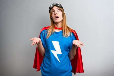 Pretty superhero girl pleading on a gray textured backgroundの写真素材