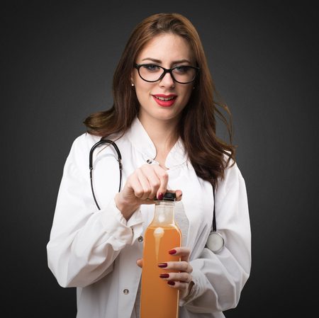 Doctor woman holding a orange juice on black backgroundの写真素材