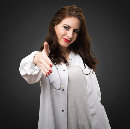 Doctor woman making a deal on black backgroundの写真素材