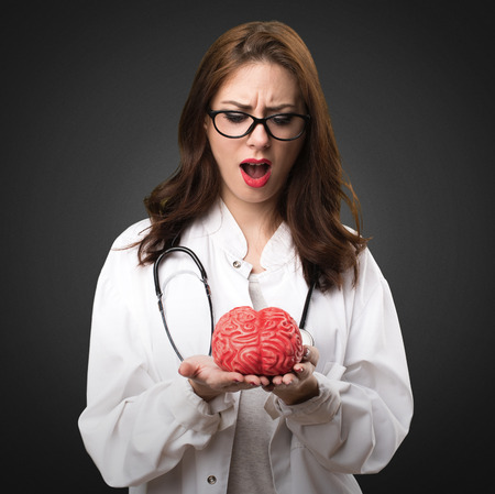 Doctor woman holding a brain on black backgroundの写真素材