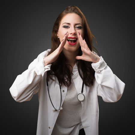 Doctor woman shouting on black backgroundの写真素材