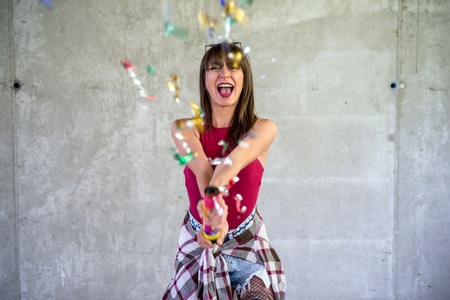 Beautiful young girl playing with confetti