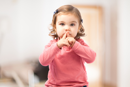 Cute girl doing silence gesture over white backgroundの写真素材