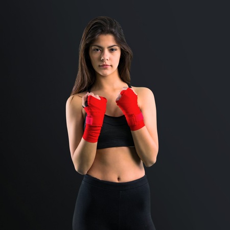 Young sport girl in boxing bandages on black background