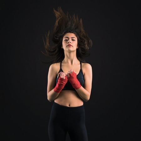 Young sport girl in boxing bandages on black background