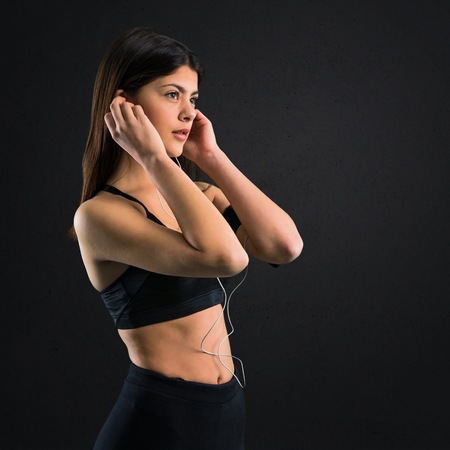 Young sport girl listening music on black backgroundの写真素材