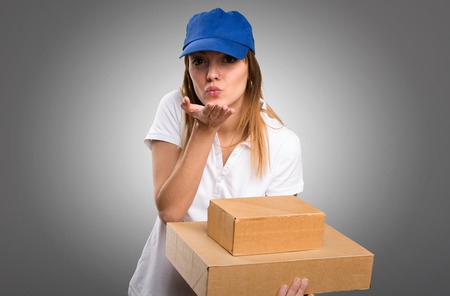 Delivery woman sending a kiss on grey backgroundの写真素材