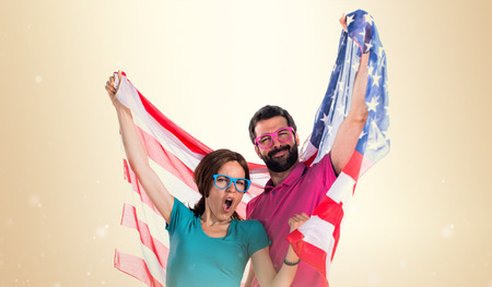 Couple in colorful clothes holding an american flagの写真素材
