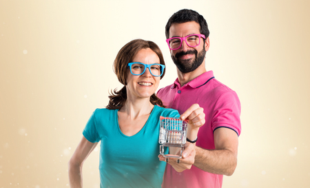 Couple in colorful clothes holding a supermarket cart toyの写真素材