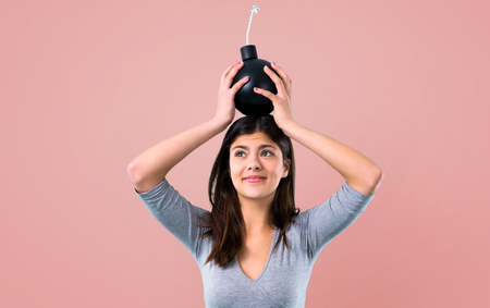 Teenager girl holding a bomb on pink backgroundの写真素材