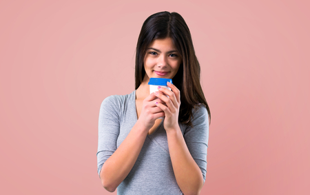 Teenager girl holding coffee to take away on pink backgroundの写真素材
