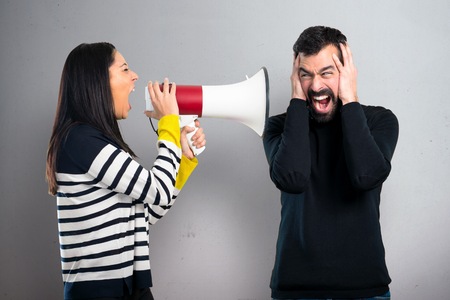 Couple holding a megaphone on grey backgroundの写真素材