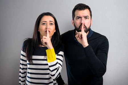 Couple making silence gesture on grey backgroundの写真素材