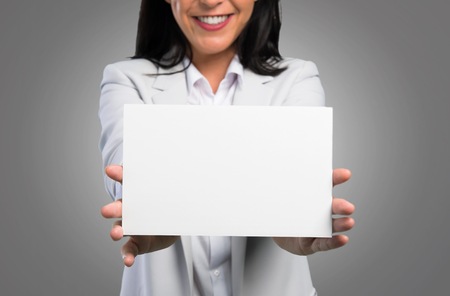 Pretty woman holding an empty placard on grey backgroundの写真素材