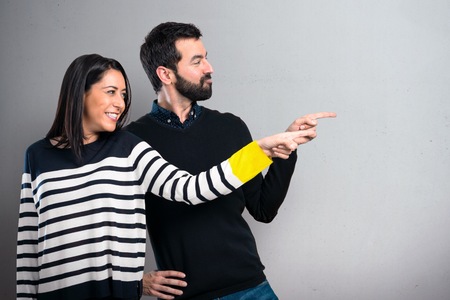Couple pointing to the lateral on grey backgroundの写真素材