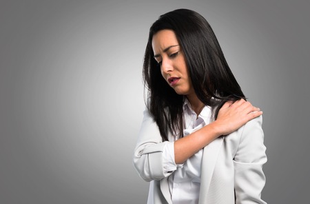 Pretty woman with shoulder pain on grey backgroundの写真素材