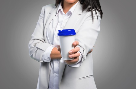 Pretty woman holding coffee to take away on grey backgroundの写真素材