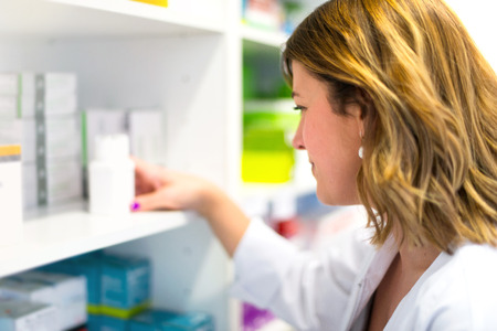 Woman customer in the pharmacy taking a medicine boxの写真素材