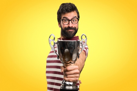 Happy Man with glasses holding a trophy on colorful backgroundの写真素材