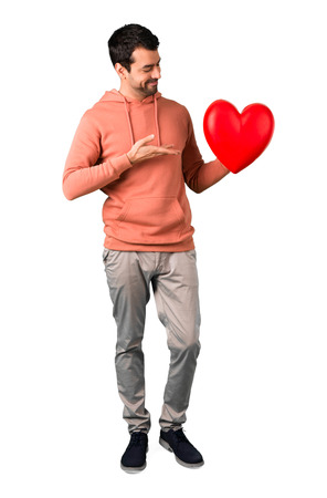 Full body of Man in a pink sweatshirt holding a big heart icon toy on isolated white backgroundの写真素材