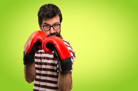 Man with glasses with boxing gloves on colorful backgroundの写真素材