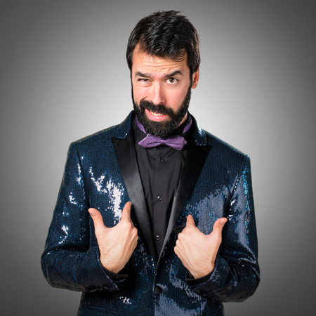 Handsome man with sequin jacket making surprise gesture on grey backgroundの写真素材