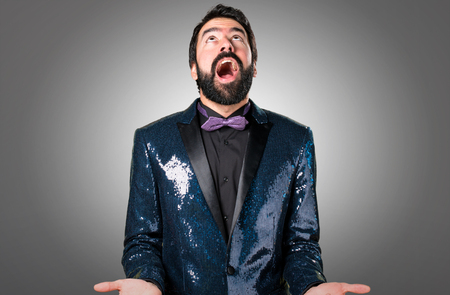 Handsome man with sequin jacket pleading on grey backgroundの写真素材