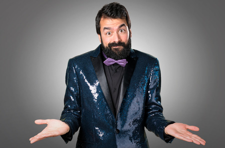 Handsome man with sequin jacket making unimportant gesture on grey backgroundの写真素材