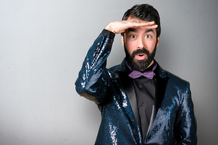 Handsome man with sequin jacket showing something on grey backgroundの写真素材