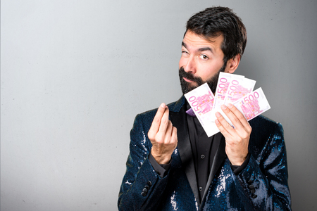 Handsome man with sequin jacket taking a lot of money on grey backgroundの写真素材