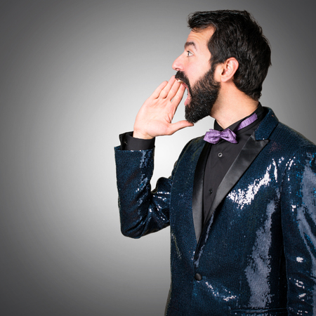 Handsome man with sequin jacket shouting on grey backgroundの写真素材