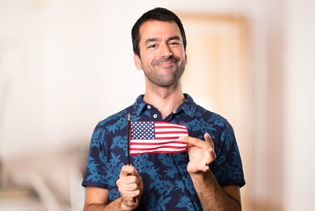 Brunette man holding an american flag inside roomの写真素材