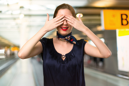 Pretty stewardess covering her eyes inside the airportの写真素材